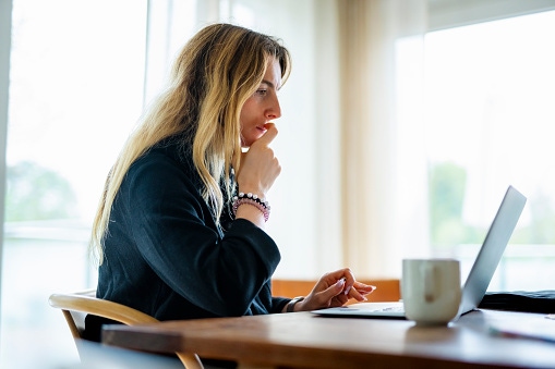 woman sits at a table with her laptop and coffee