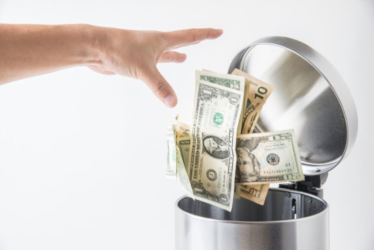 a hand throwing dollar bills into a bin