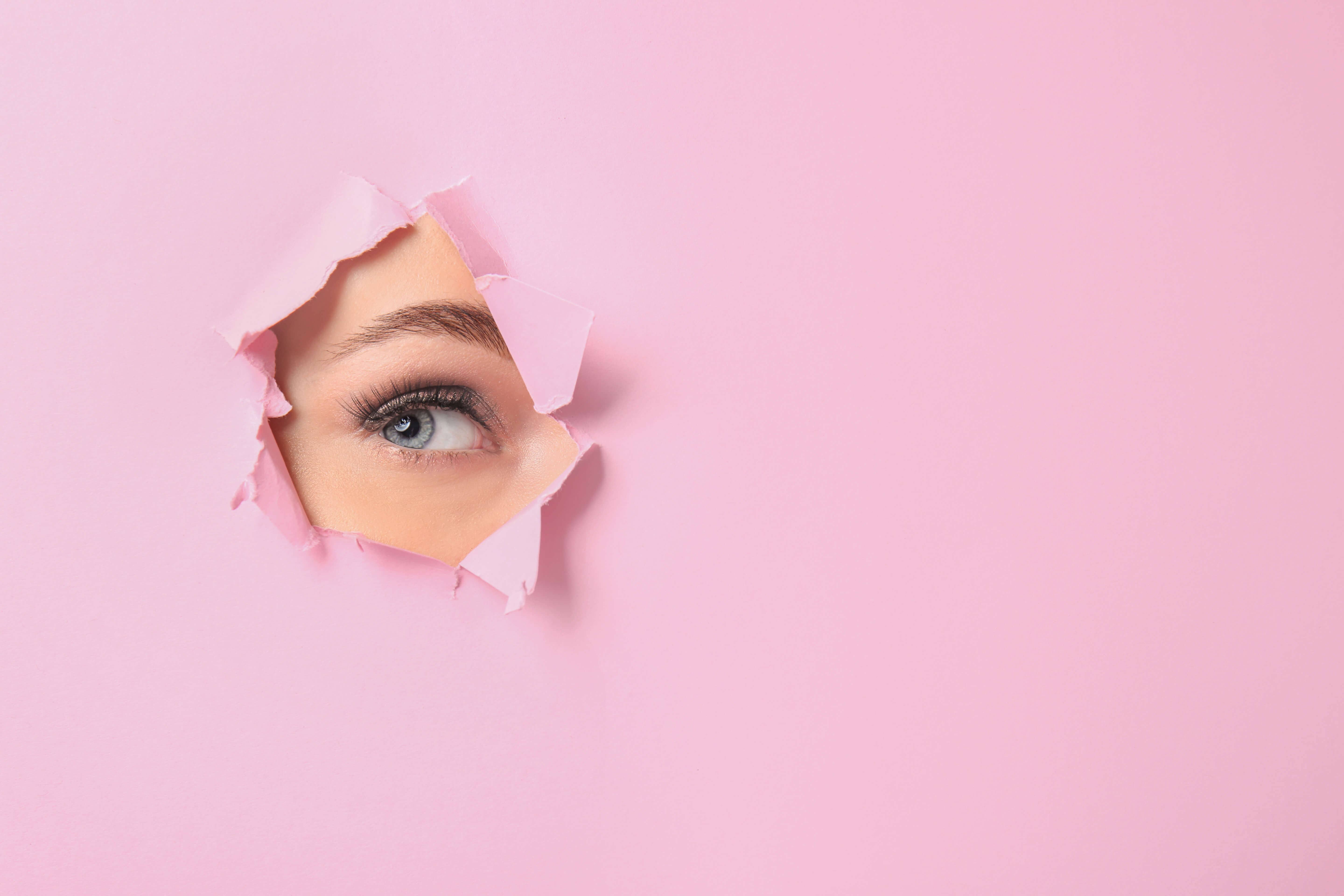 pink paper background with a hole and an eye 